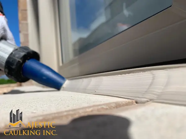Worker caulking a windowe